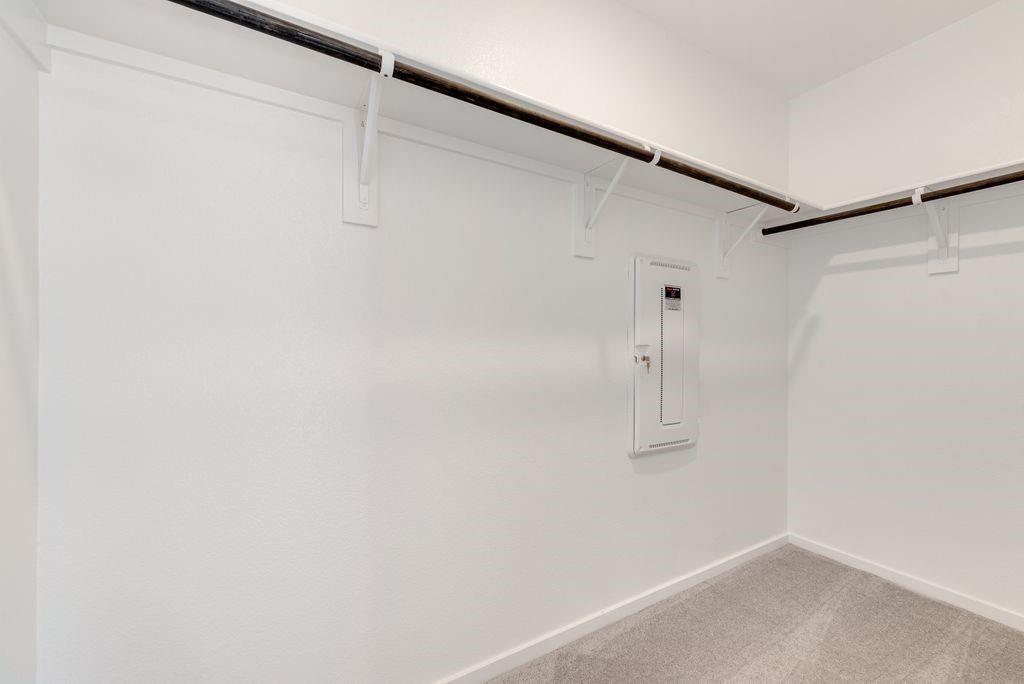 Spacious closet with electric panel and light carpet