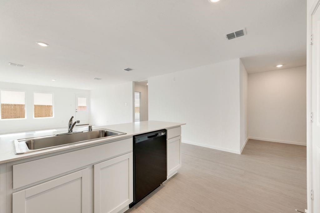 Kitchen with dishwasher, recessed lighting, light wood-style floors, light countertops, and white cabinets Kitchen with dishwasher, recessed lighting, light wood-style floors, light countertops, and white cabinets