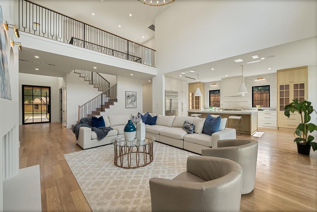 Open-concept living space featuring high ceilings, wood-finish flooring, and a contemporary kitchen with an island