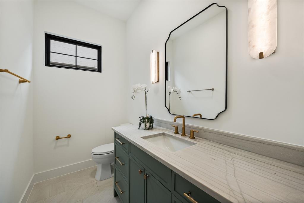 Bathroom featuring a green vanity with brass hardware, a white undermount sink, and a light-toned countertop