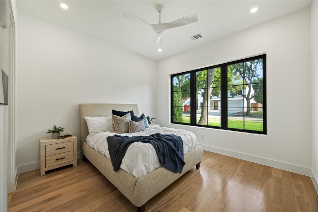Bedroom featuring wood-finish flooring, a contemporary ceiling fan, recessed lighting, and a large window with black gridded frames