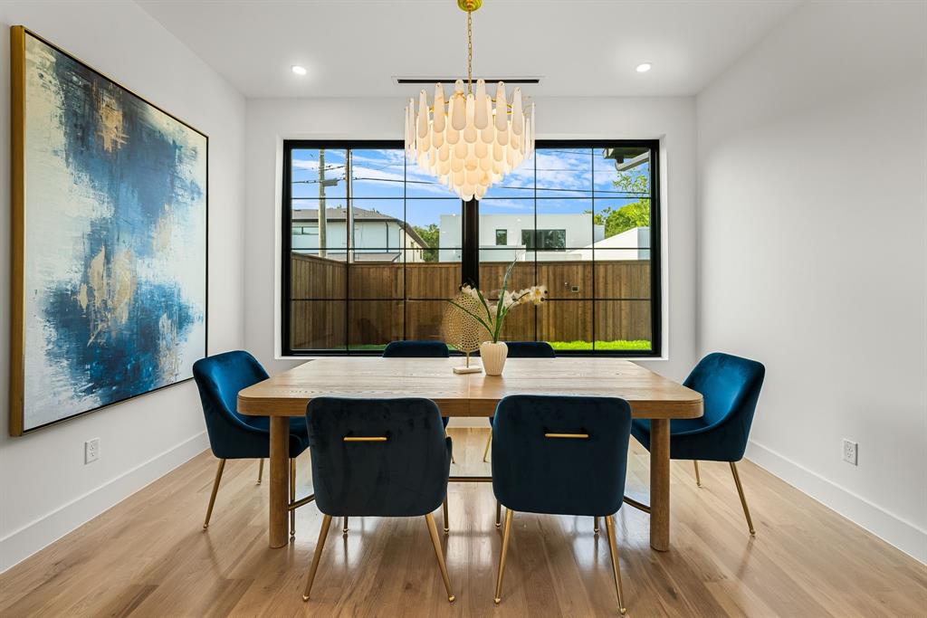 Dining area featuring wood-finish flooring, a contemporary chandelier, and a large black-framed window