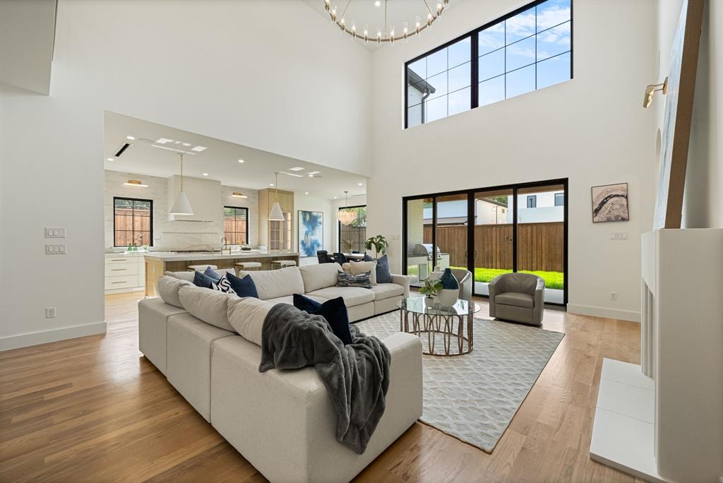 Open-concept living space featuring high ceilings, wood-finish flooring, and a fireplace with a white mantel