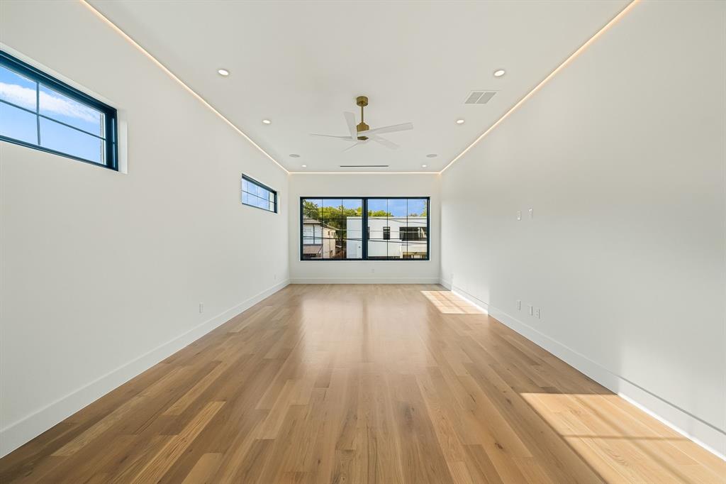 Spacious room featuring wood-finish flooring and multiple windows with dark framing