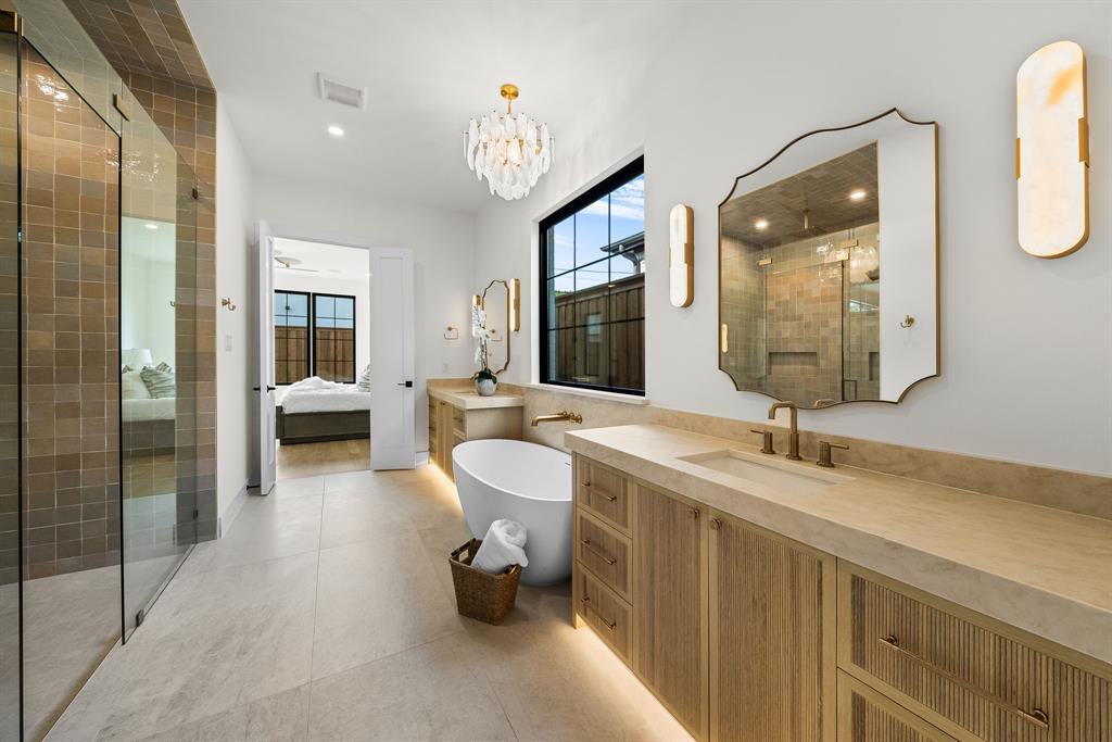 Contemporary bathroom featuring a freestanding tub, dual vanities with integrated sinks, a walk-in shower with glass enclosure, and large format floor tiling