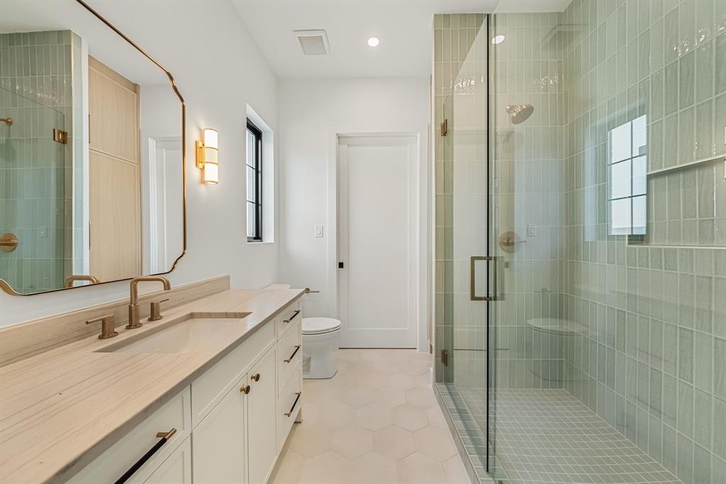 Bathroom featuring a glass-enclosed shower with vertical tile, a built-in shower bench, and a rectangular niche