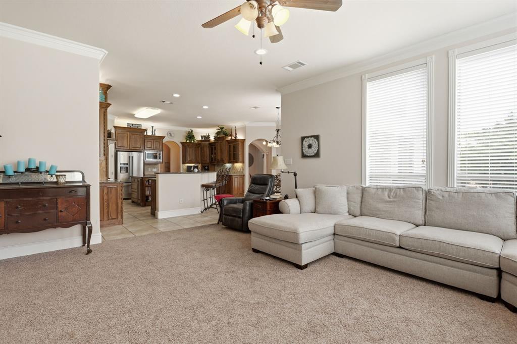 Open-concept living space featuring carpet flooring and crown molding
