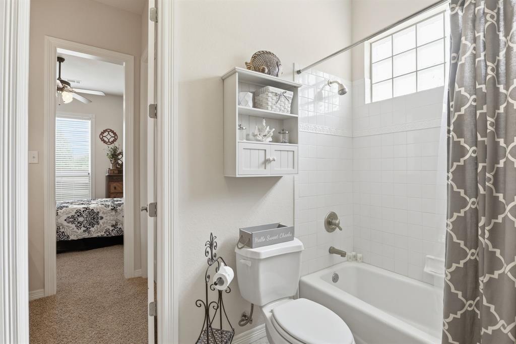 Bathroom featuring a white bathtub, ceramic tile surround, and a glass block window for natural light