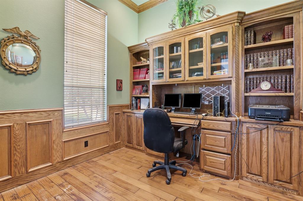 Dedicated office space featuring extensive built-in custom cabinetry, integrated desk area, and wood-finish flooring