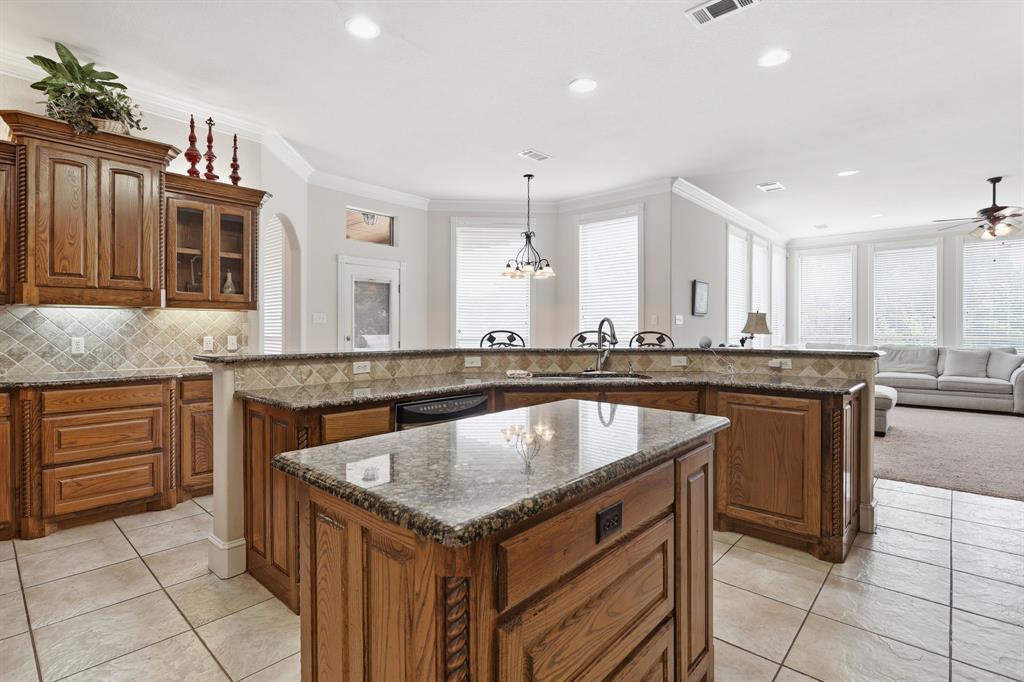 Kitchen featuring a central island with a stone-finish countertop, wood cabinetry, and a tile backsplash