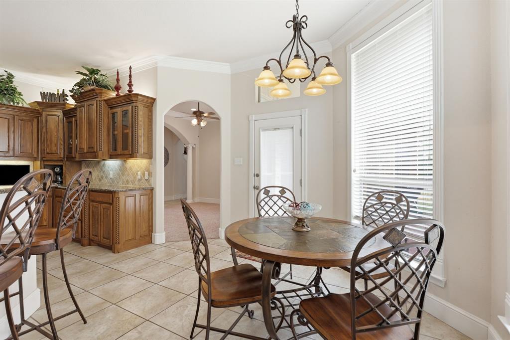 Kitchen dining area featuring a pendant chandelier, large window with blinds, and tile flooring