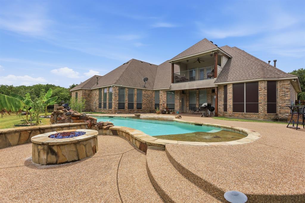 Expansive exposed aggregate patio surrounding a freeform swimming pool with integrated rock waterfall feature