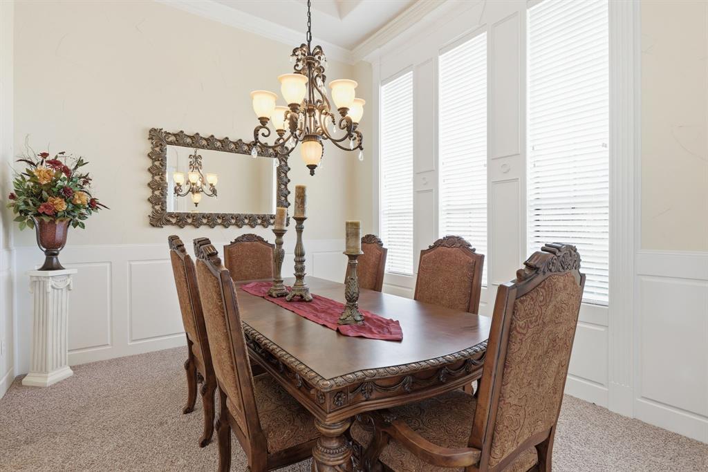 Formal dining area featuring a decorative chandelier, wainscoting, crown molding, and multiple tall windows