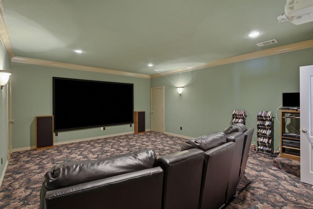 Dedicated media room featuring a large projection screen, recessed ceiling lighting, and wall sconces