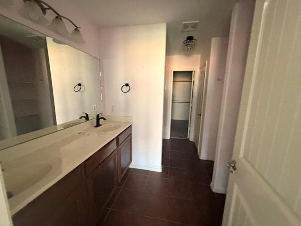 Bathroom vanity featuring two integrated sinks, dark wood cabinetry, a large wall-mounted mirror, and a three-light fixture