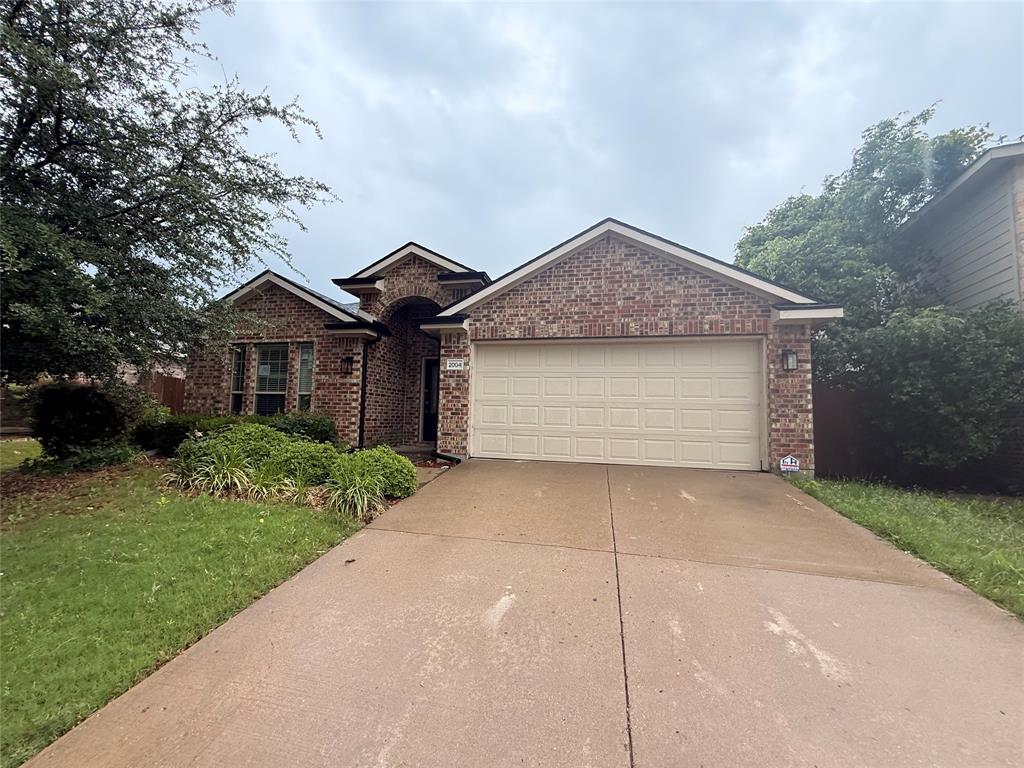 Brick exterior featuring a two-car garage, concrete driveway, and established front landscaping Brick exterior featuring a two-car garage, concrete driveway, and established front landscaping