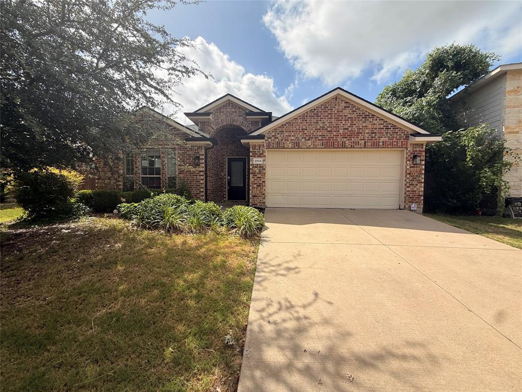 Brick exterior with a prominent arched entry, attached two-car garage, and a concrete driveway