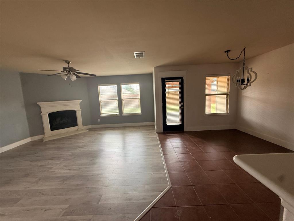 Open-concept living area featuring wood-finish flooring, a white mantel fireplace, and a ceiling fan