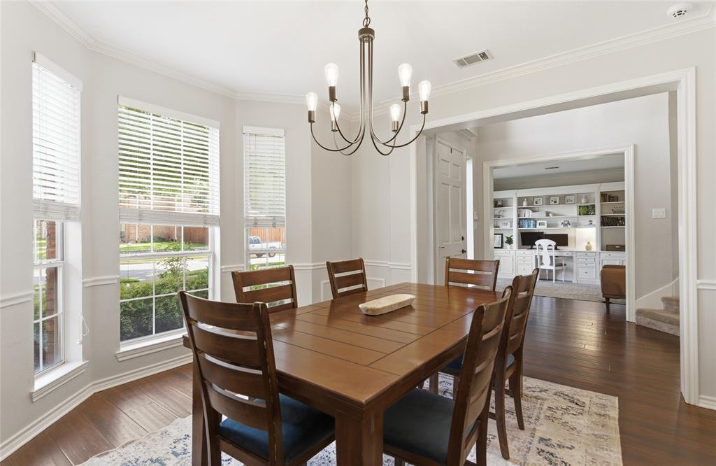 Formal dining area featuring bay windows with blinds, crown molding, and wood-finish flooring