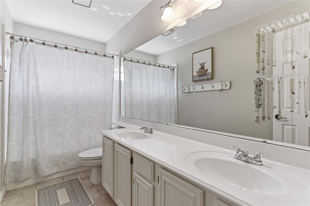 Bathroom featuring a dual vanity with integrated sinks, chrome faucets, and white cabinetry