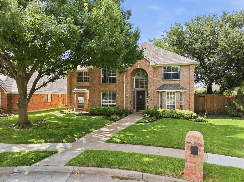 Two-story brick facade residence with an arched entry, bay window, and gabled roof