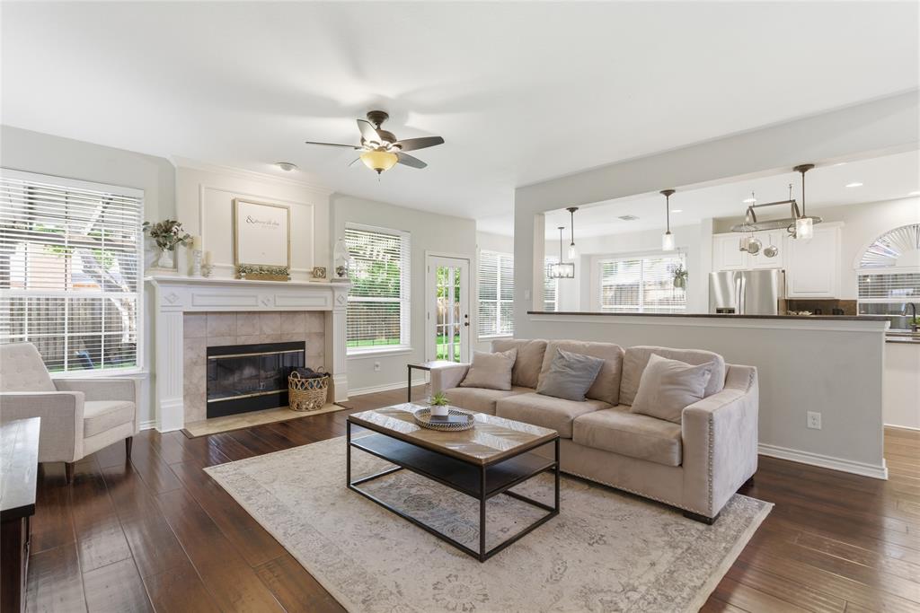 Living area featuring wood-finish flooring, a decorative fireplace with a tile surround and mantel, and white interior trim Living area featuring wood-finish flooring, a decorative fireplace with a tile surround and mantel, and white interior trim