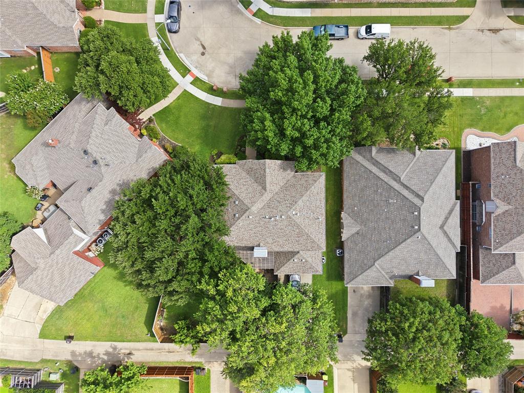 Aerial perspective showcasing a residential property with a shingle roof and surrounding green landscaping