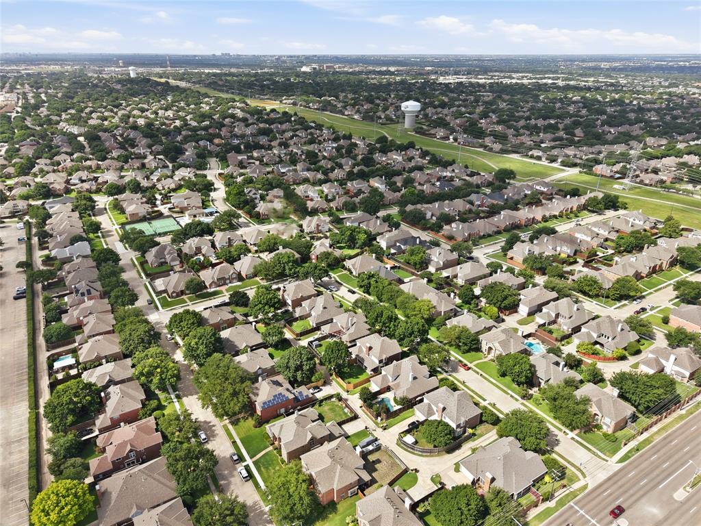 Aerial perspective showcasing a residential neighborhood with tree-lined streets, numerous single-family homes, and established landscaping