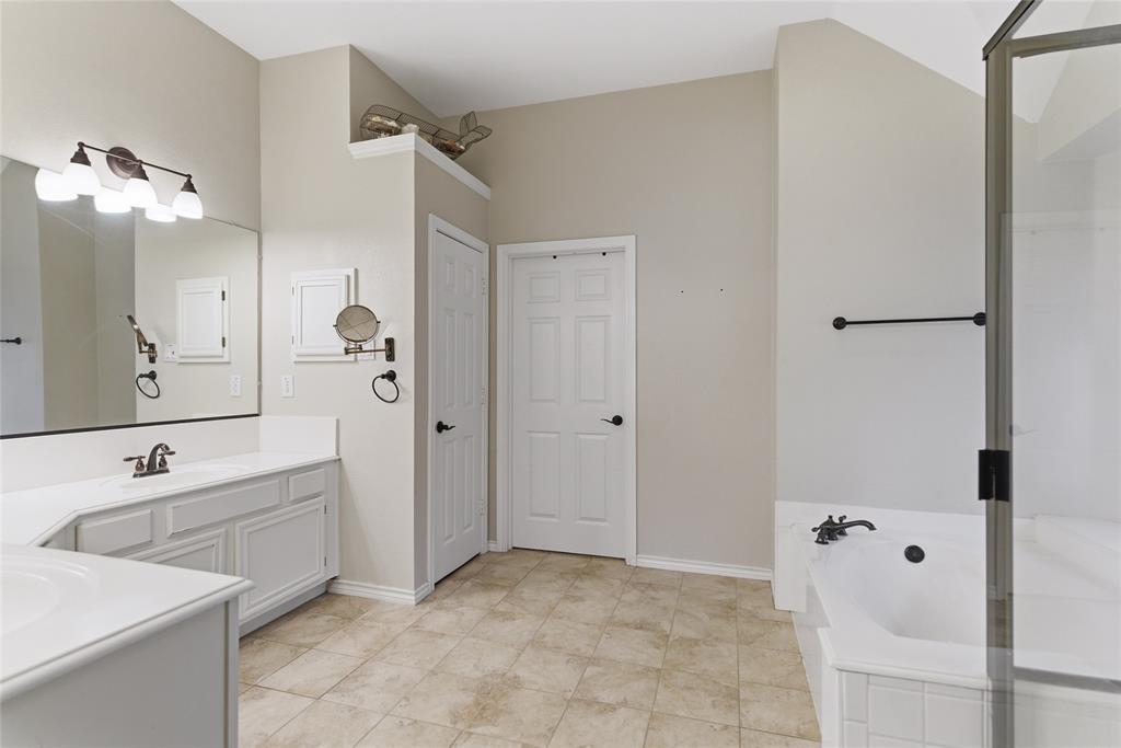 Bathroom featuring a large vanity with ample countertop space, a built-in tub, a separate shower enclosure, and tiled flooring