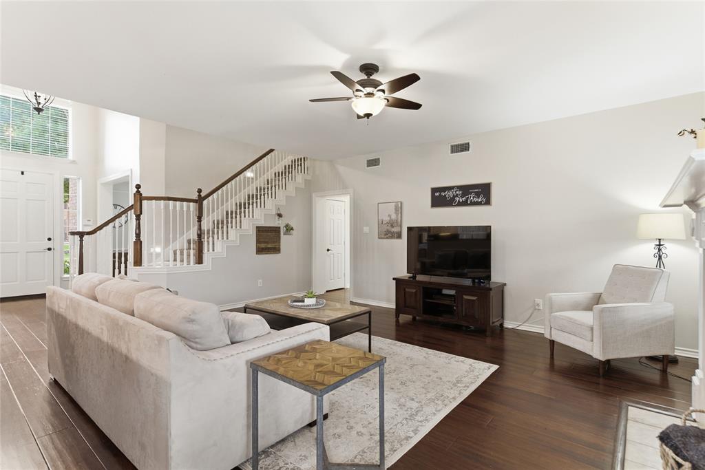 Living area featuring rich wood-finish flooring, a two-story entryway, and a prominent staircase with white balusters and dark wood handrails