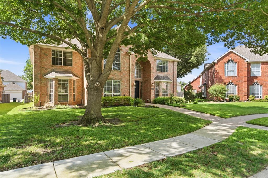 Brick exterior with multiple bay windows, an arched entry, and a mature tree providing shade Brick exterior with multiple bay windows, an arched entry, and a mature tree providing shade