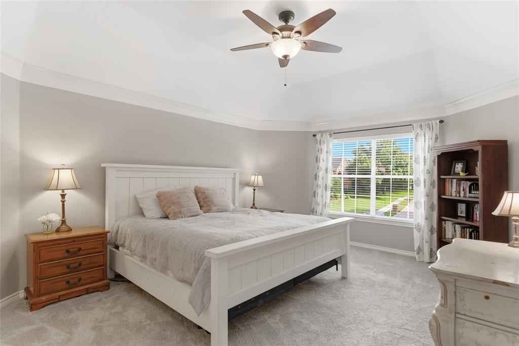 Spacious room featuring vaulted ceilings, crown molding, a large window with blinds, carpeted flooring, and a built-in ceiling fan with lighting