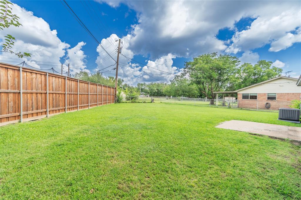 Expansive backyard featuring a manicured lawn, full wood privacy fencing, and a concrete patio pad