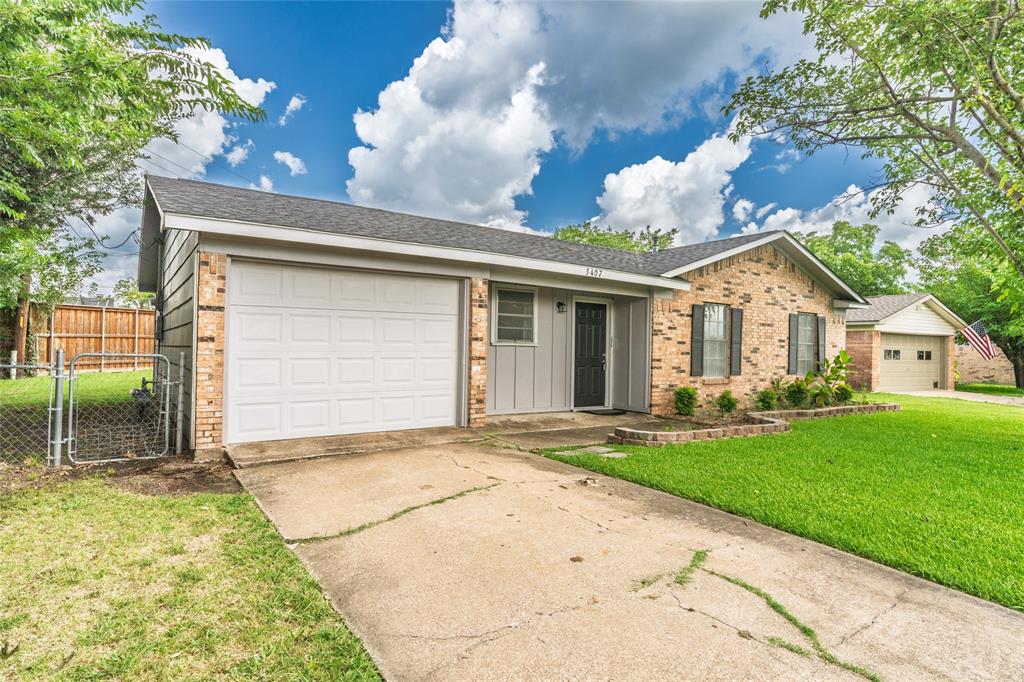 Brick and siding exterior with an attached garage, a paved driveway, and a chain-link fence