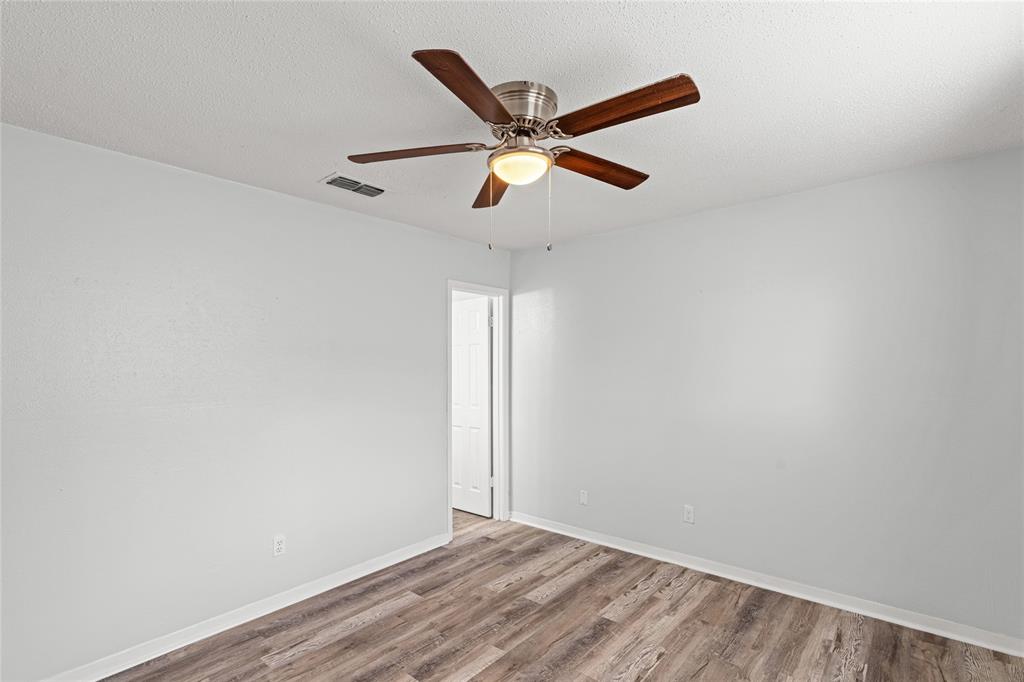 Room featuring wood-finish flooring, light grey walls, white baseboards, and a ceiling fan with integrated lighting