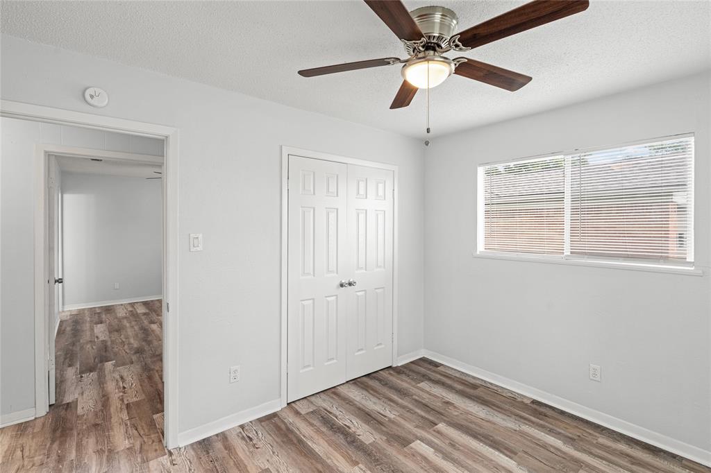 Room featuring wood-finish flooring, a ceiling fan with integrated lighting, a double-door closet, and a window with horizontal blinds