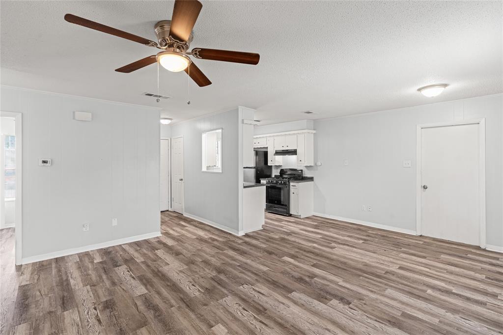 Spacious room featuring wood-finish flooring, light gray walls, and a ceiling fan with integrated lighting