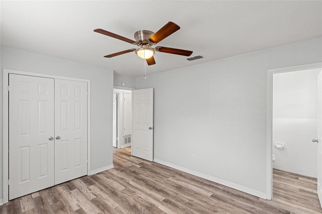 Spacious room featuring wood-finish flooring, a ceiling fan with light fixture, and white bi-fold closet doors