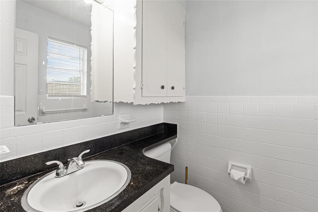 Bathroom featuring a vanity with an integrated sink, dark countertop, and chrome faucet