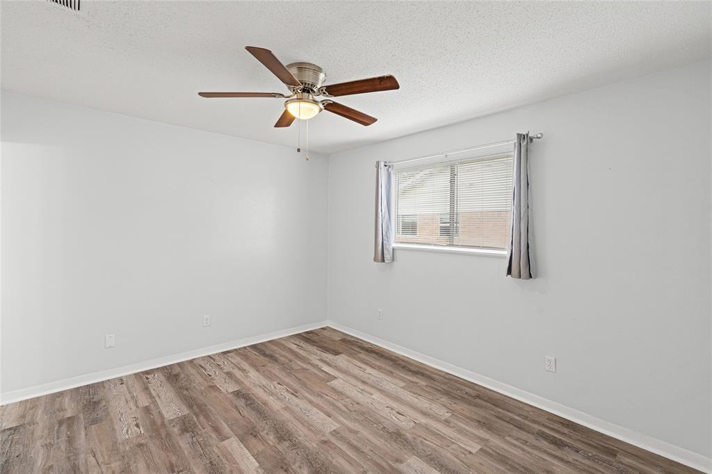 Spacious room featuring wood-finish flooring and a ceiling fan with integrated lighting