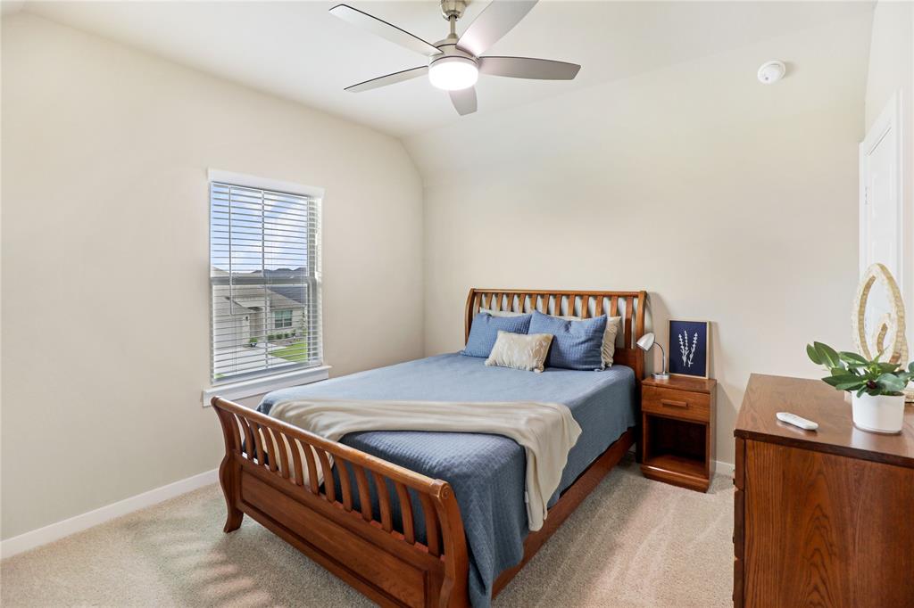 Carpeted bedroom featuring a ceiling fan with integrated lighting, a window with horizontal blinds, and neutral wall tones