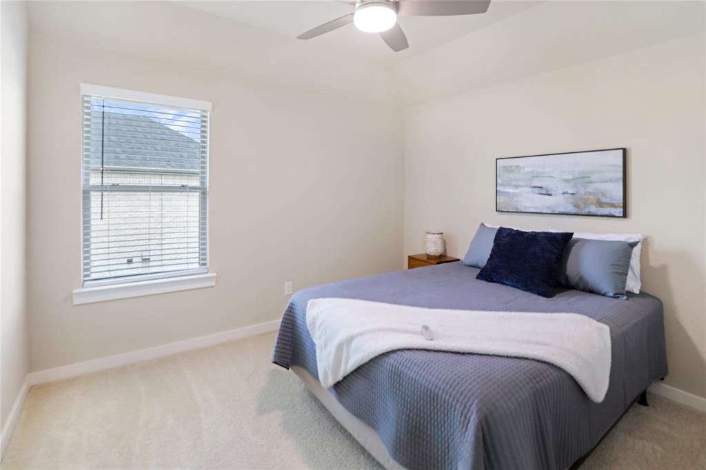 Bedroom featuring a vaulted ceiling with a ceiling fan, a single window with blinds, light-toned walls, and carpet flooring