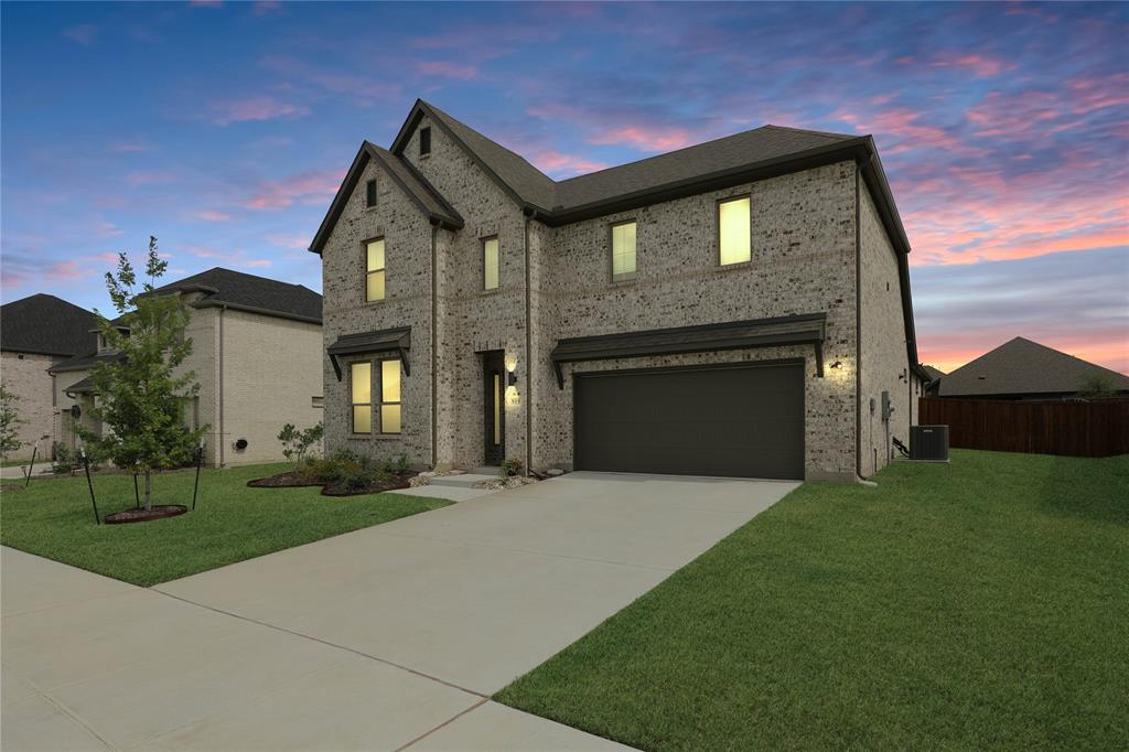 Two-story brick facade residence featuring an attached garage, covered entryway, and a concrete driveway