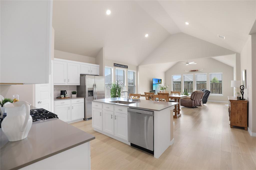 Kitchen featuring white cabinetry, a center island with sink, stainless steel appliances, and light wood-finish flooring
