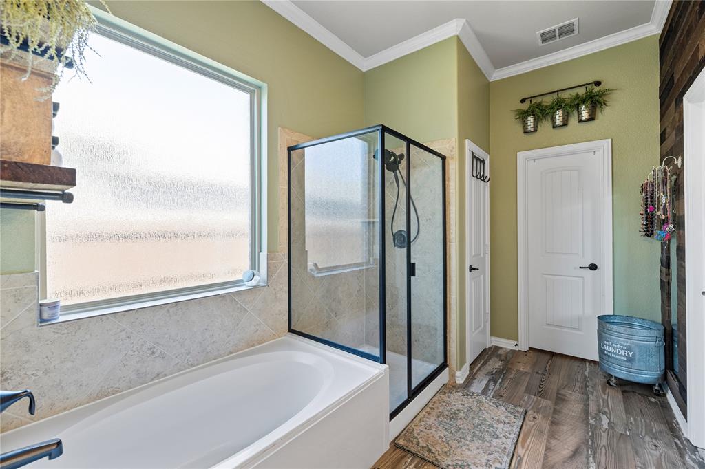 Bathroom with ornamental molding, plenty of natural light, separate shower and tub, and hardwood / wood-style floors