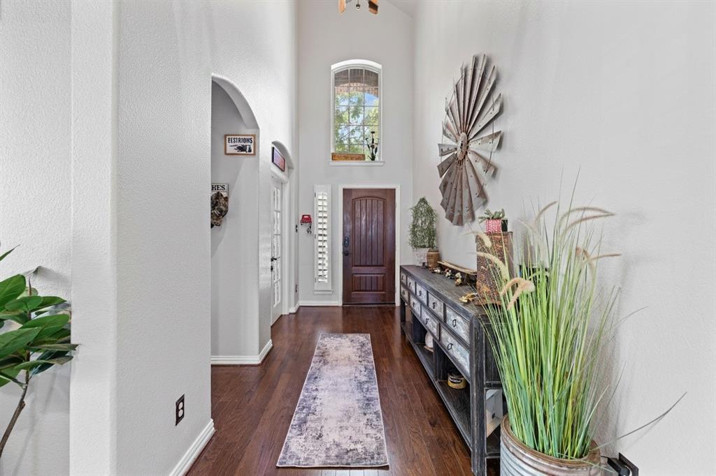 Entryway featuring high ceilings, wood-finish flooring, a dark wood-paneled door, and an arched transom window