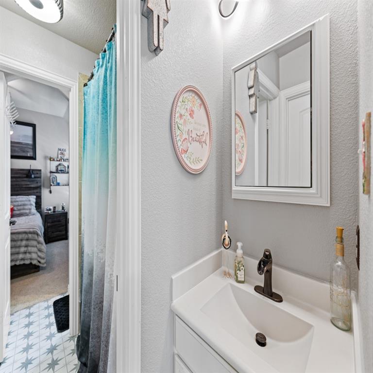 Bathroom vanity featuring a white countertop with integrated sink and dark-finish faucet