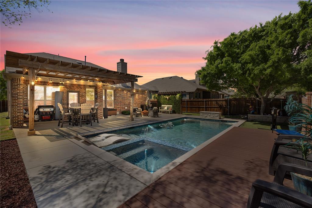 Pool at dusk featuring a patio area, an in ground hot tub, a wooden deck, and a pergola