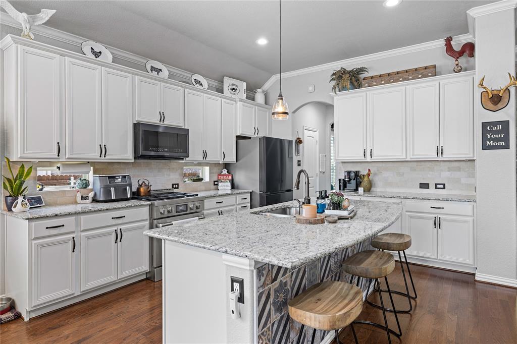 Kitchen with decorative light fixtures, crown molding, stainless steel appliances, and dark wood-type flooring