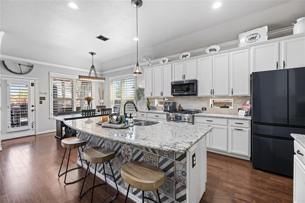 Kitchen with a healthy amount of sunlight, pendant lighting, stainless steel appliances, and dark hardwood / wood-style floors Kitchen with a healthy amount of sunlight, pendant lighting, stainless steel appliances, and dark hardwood / wood-style floors